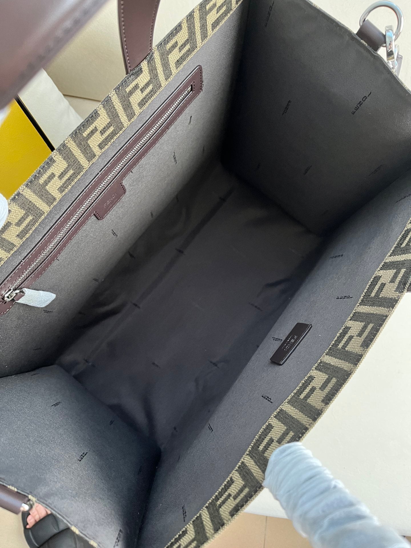 FENDI spacious tote bag in recycled jacquard fabric featuring gray and black FF motif. Featuring fabric-lined interior compartments, interior zip pocket and silver-tone hardware.